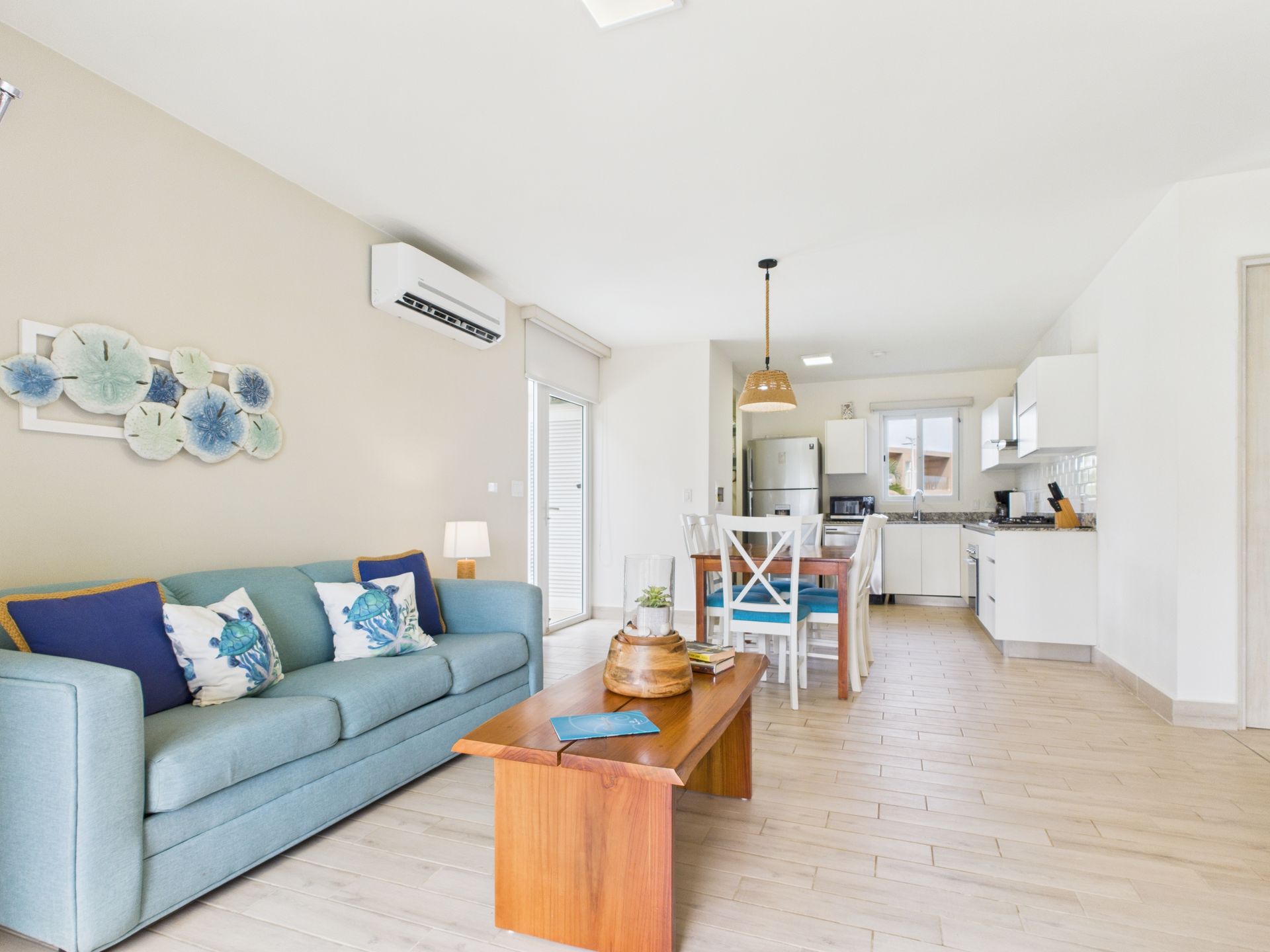 Living room with blue sofa, wooden coffee table, and open kitchen.