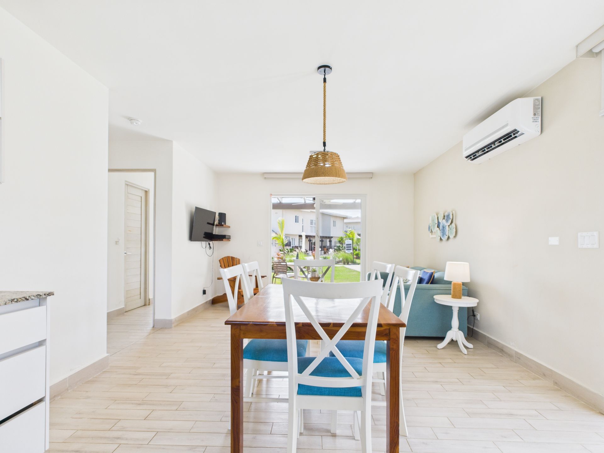 Dining room with wooden table, white chairs, and a pendant light.