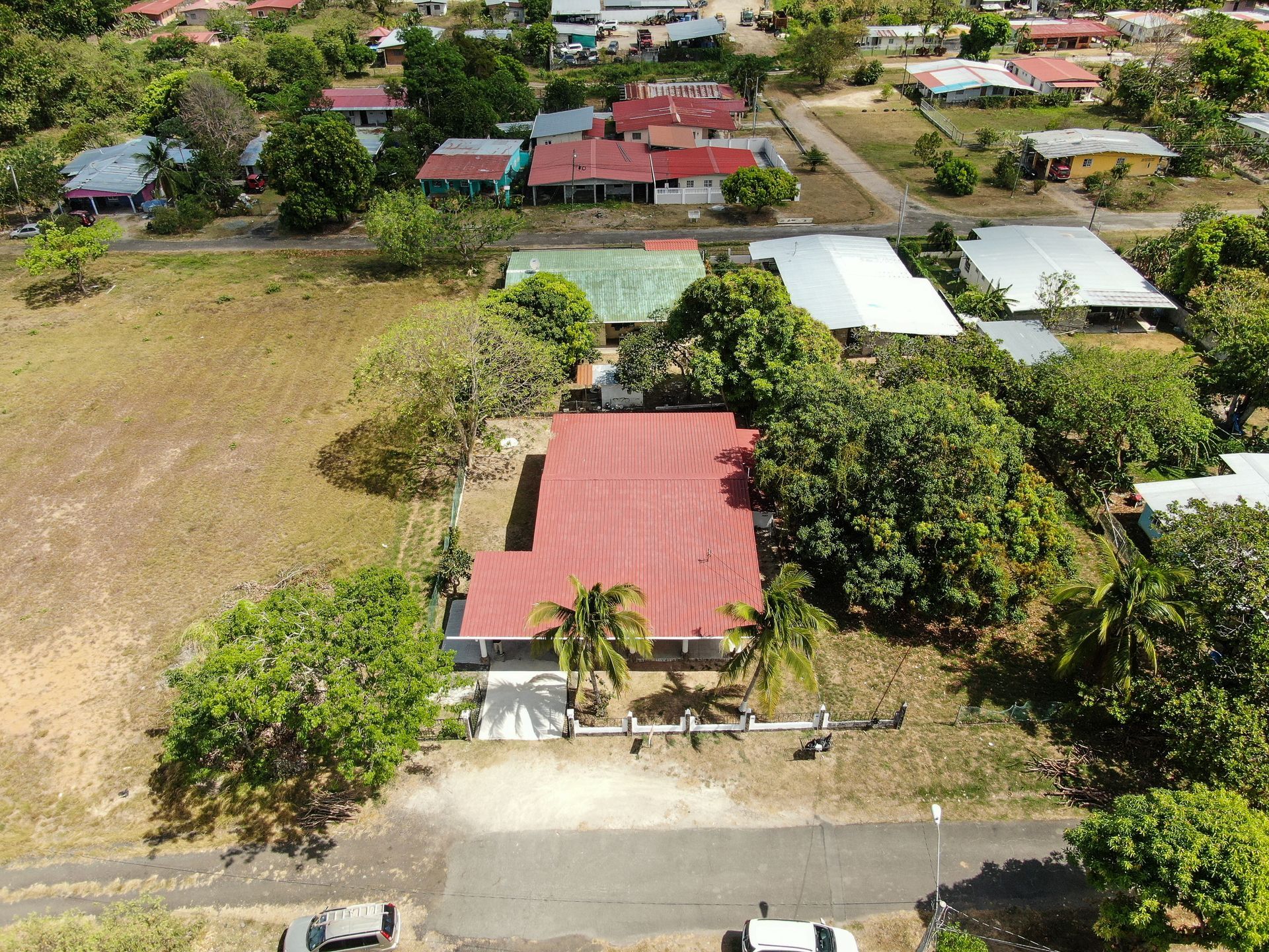 Vista aérea de un barrio residencial en anton cocle con una casa central que presenta un gran tejado rojo rodeado de árboles verdes.