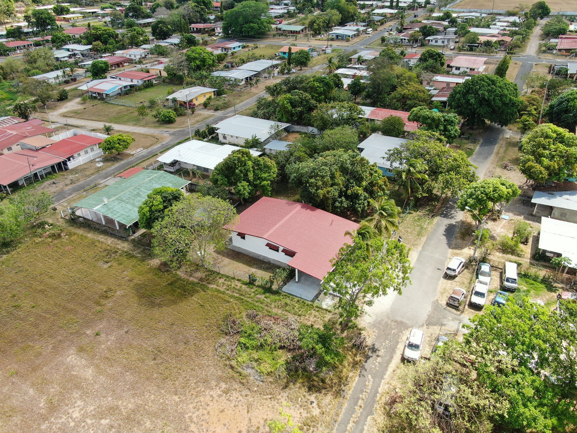 Vista aérea de un barrio residencial en anton cocle con una casa central que presenta un gran tejado rojo rodeado de árboles verdes.
