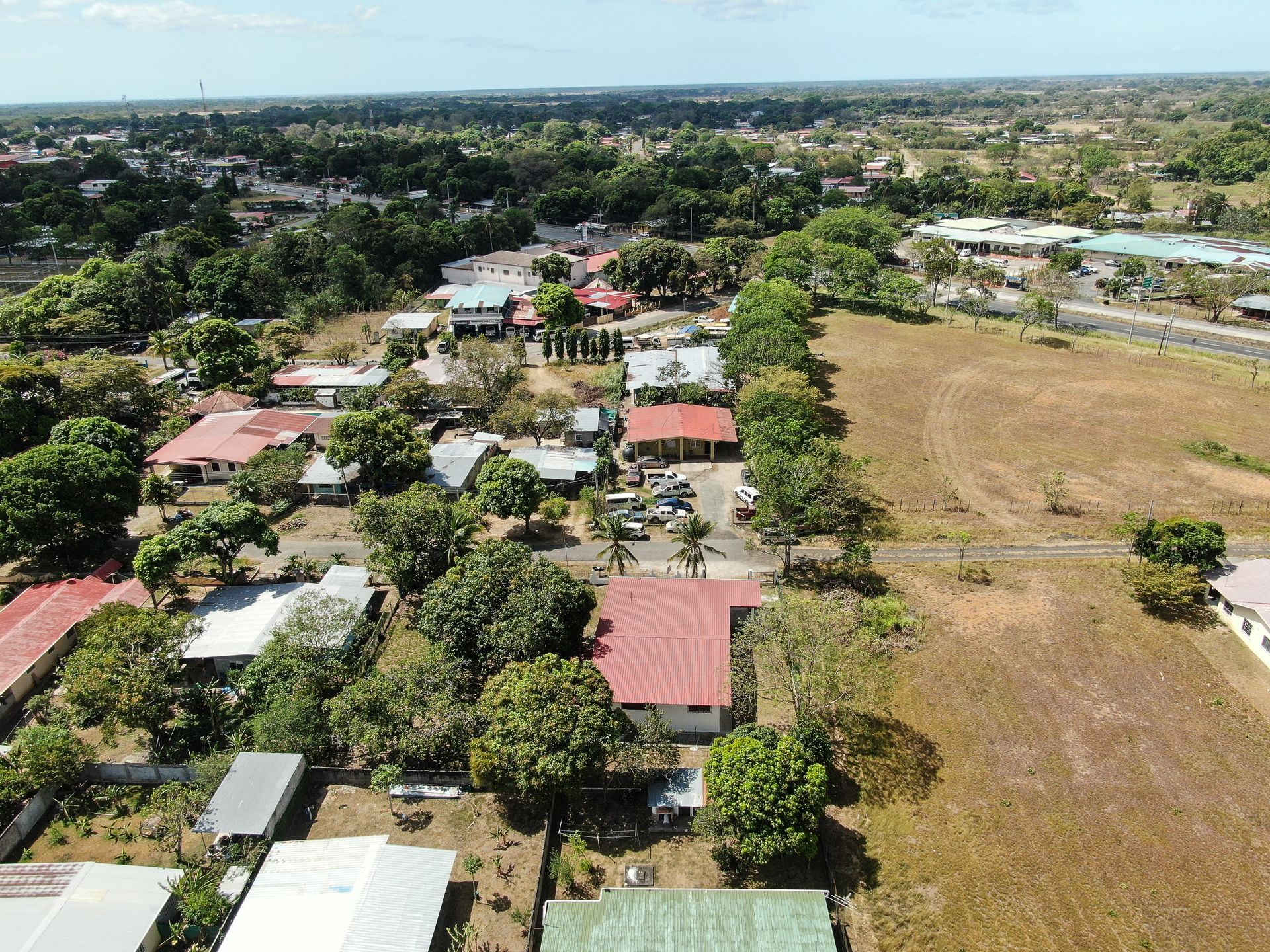 Vista aérea de un barrio residencial en anton cocle con una casa central que presenta un gran tejado rojo rodeado de árboles verdes.