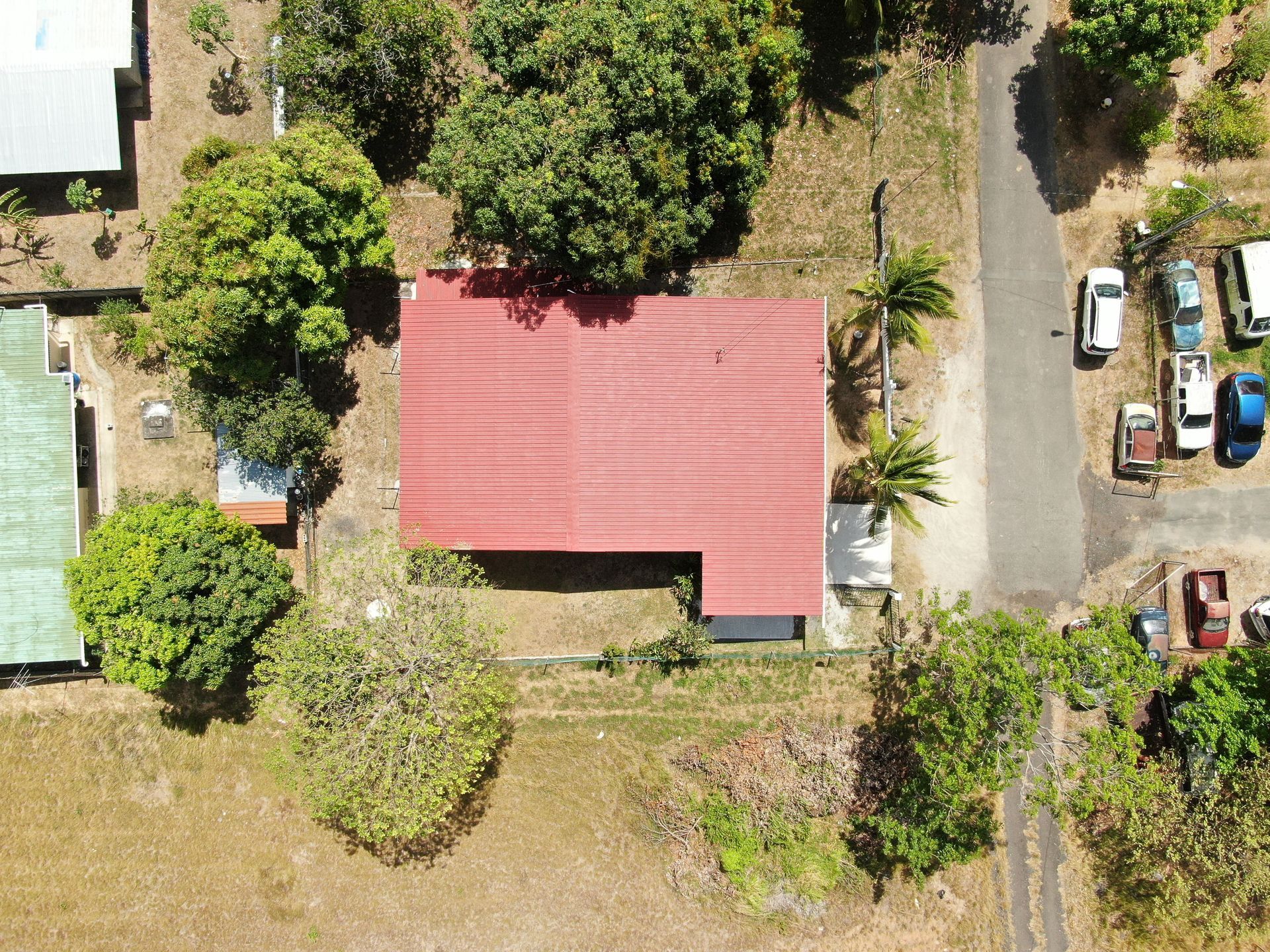 Vista aérea de un barrio residencial en anton cocle con una casa central que presenta un gran tejado rojo rodeado de árboles verdes.