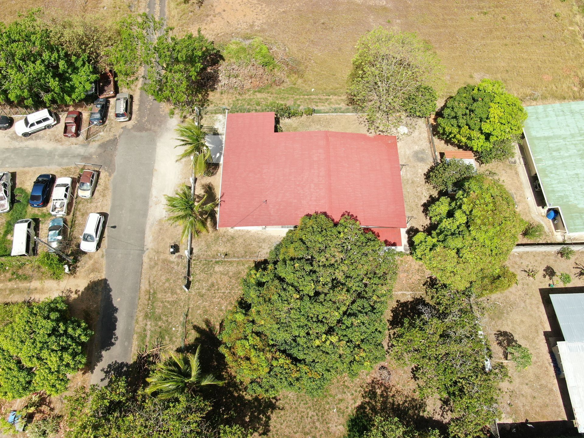 Vista aérea de un barrio residencial en anton cocle con una casa central que presenta un gran tejado rojo rodeado de árboles verdes.