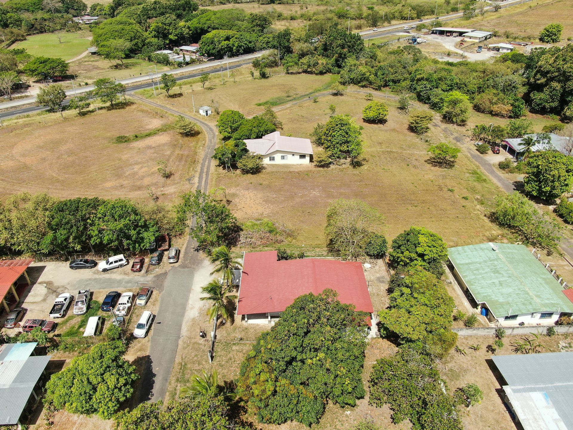Vista aérea de un barrio residencial en anton cocle con una casa central que presenta un gran tejado rojo rodeado de árboles verdes.