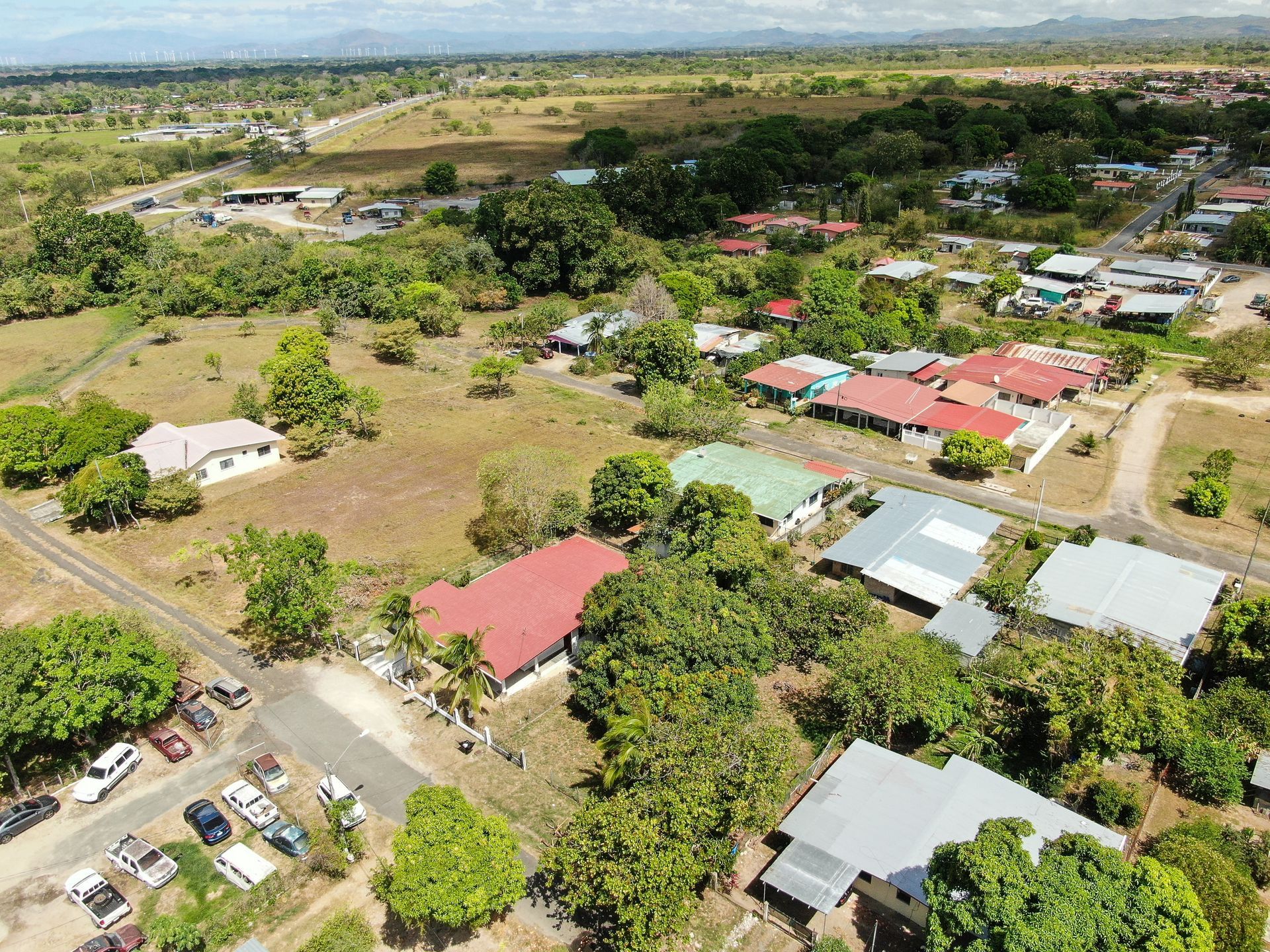 Vista aérea de un barrio residencial en anton cocle con una casa central que presenta un gran tejado rojo rodeado de árboles verdes.