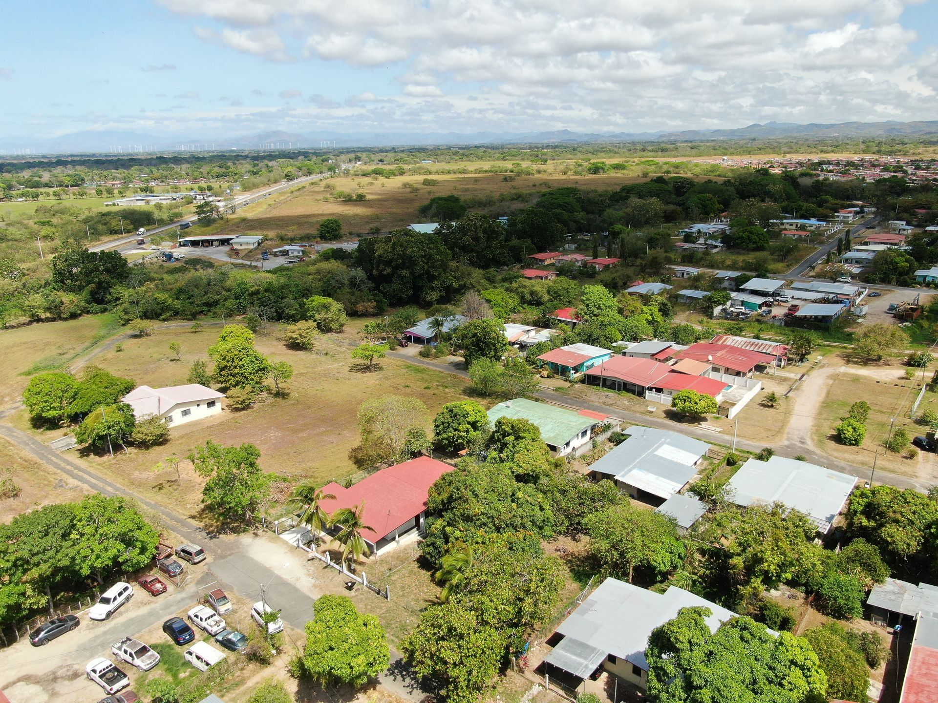 Vista aérea de un barrio residencial en anton cocle con una casa central que presenta un gran tejado rojo rodeado de árboles verdes.
