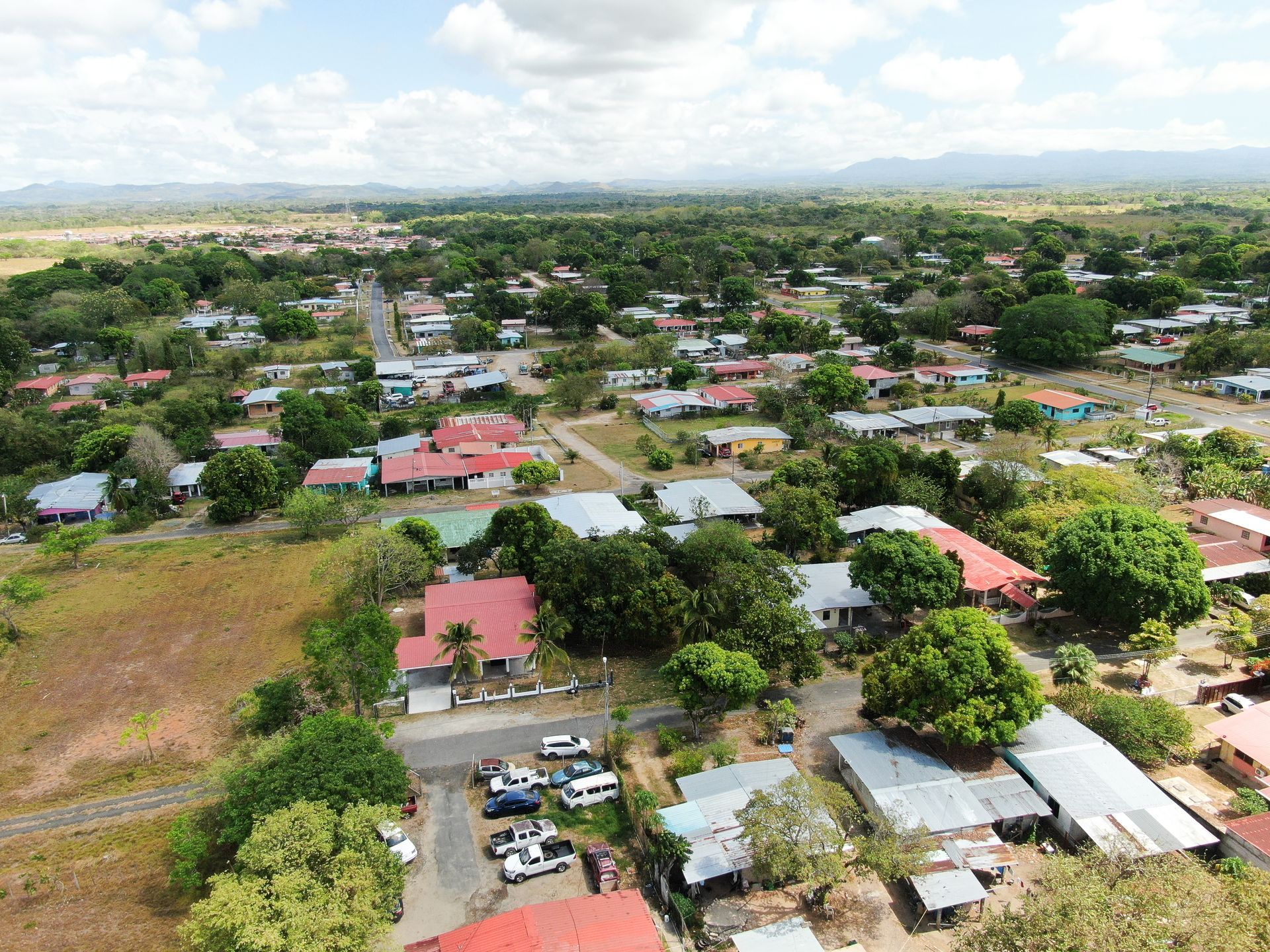 Vista aérea de un barrio residencial en anton cocle con una casa central que presenta un gran tejado rojo rodeado de árboles verdes.