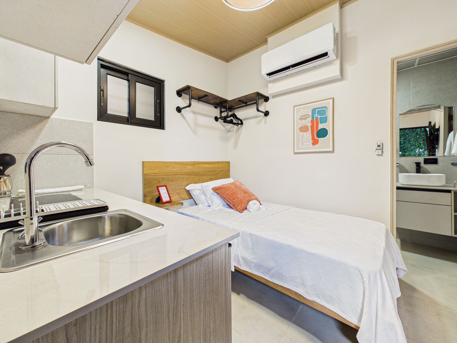 Este estudio compacto cuenta con una pequeña cocina americana, una cama individual, un perchero de pared y un baño privado. en Bethania, Ciudad de Panamá. Fotografía de real estate