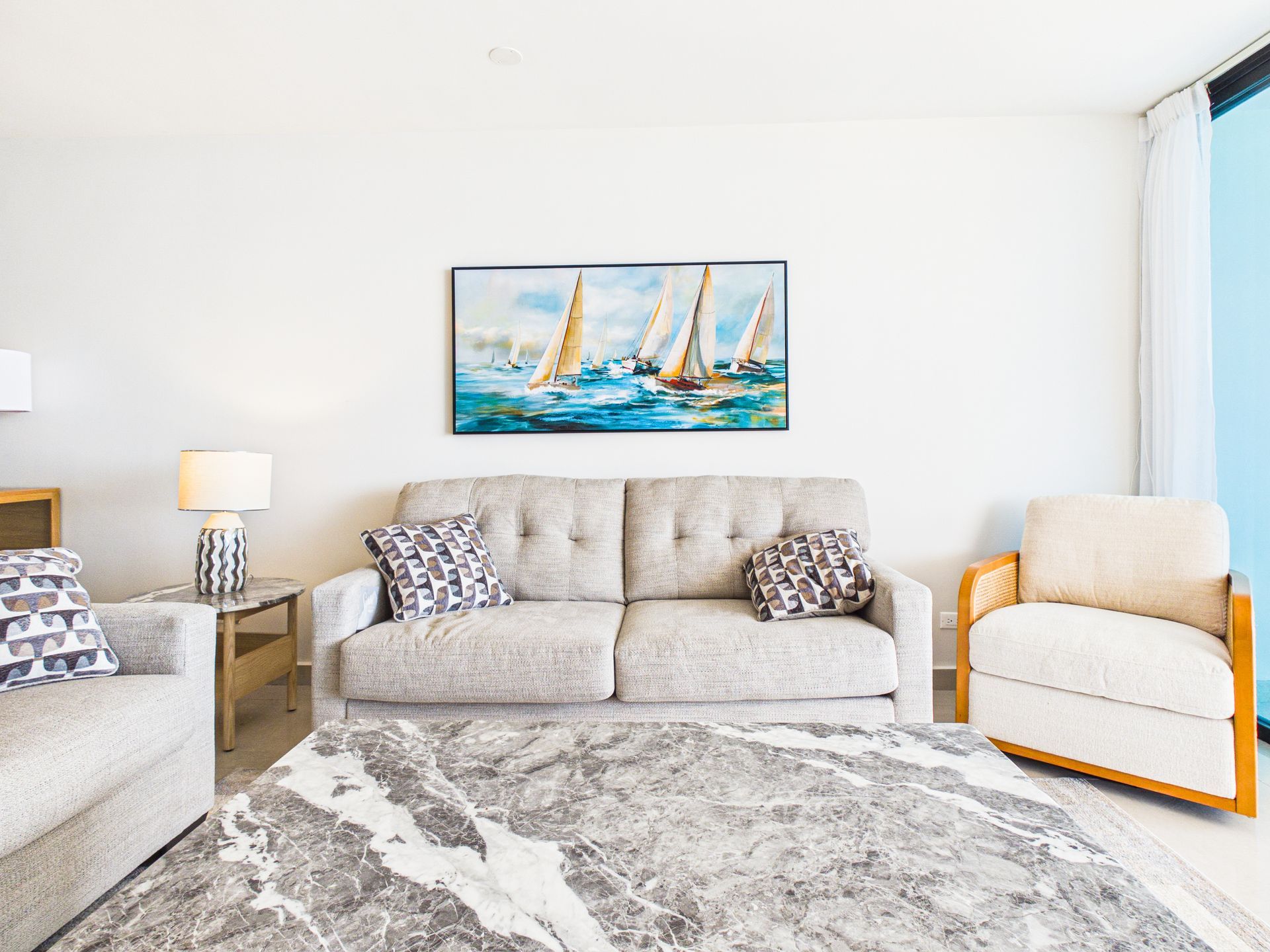 Casa de una sola planta con techo plano, patio delantero cercado y entrada central, vista desde una calle de grava bajo un cielo azul.