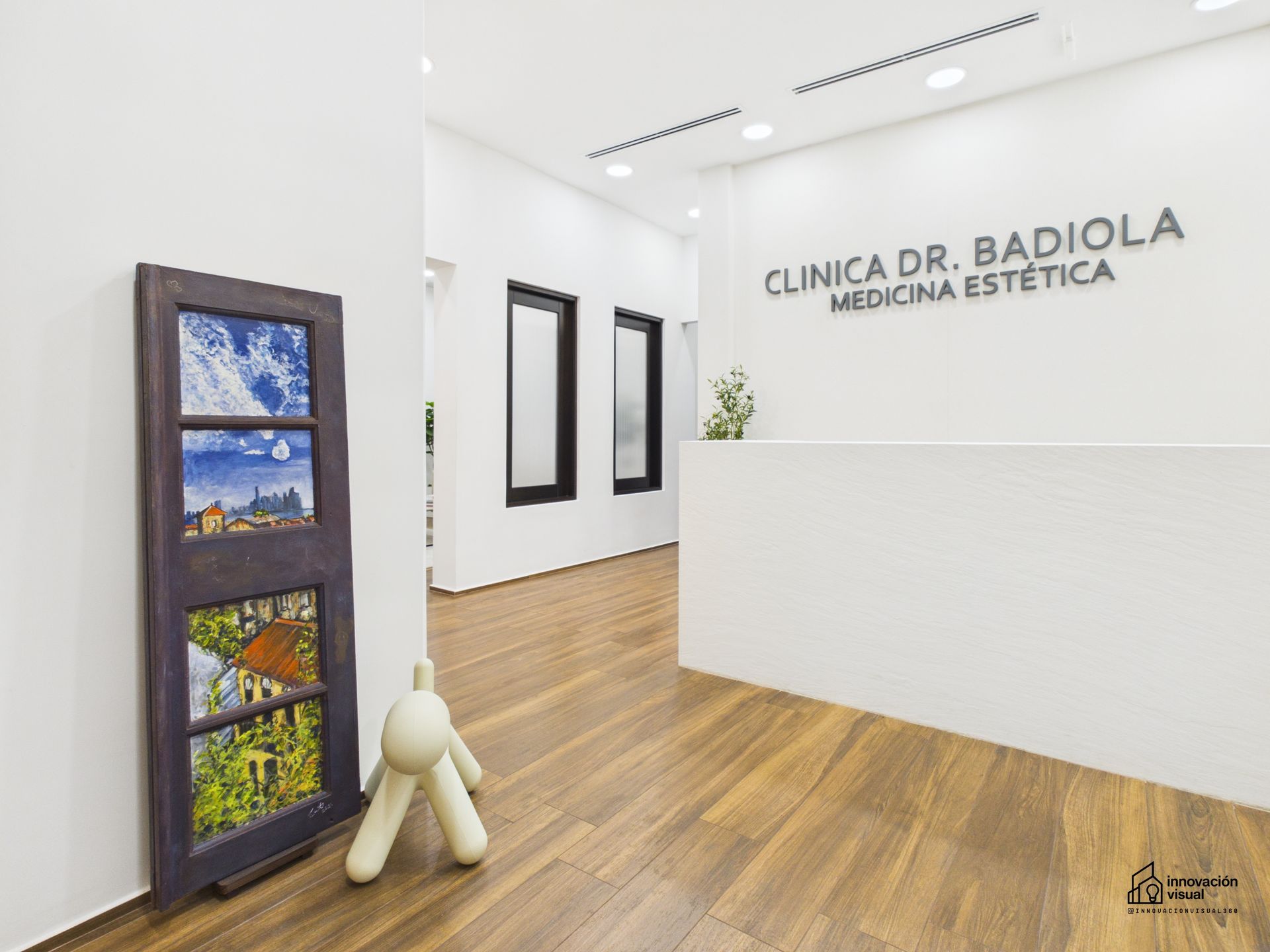 Interior of a modern medical clinic with a wooden floor, minimalist decor, and a framed art piece.