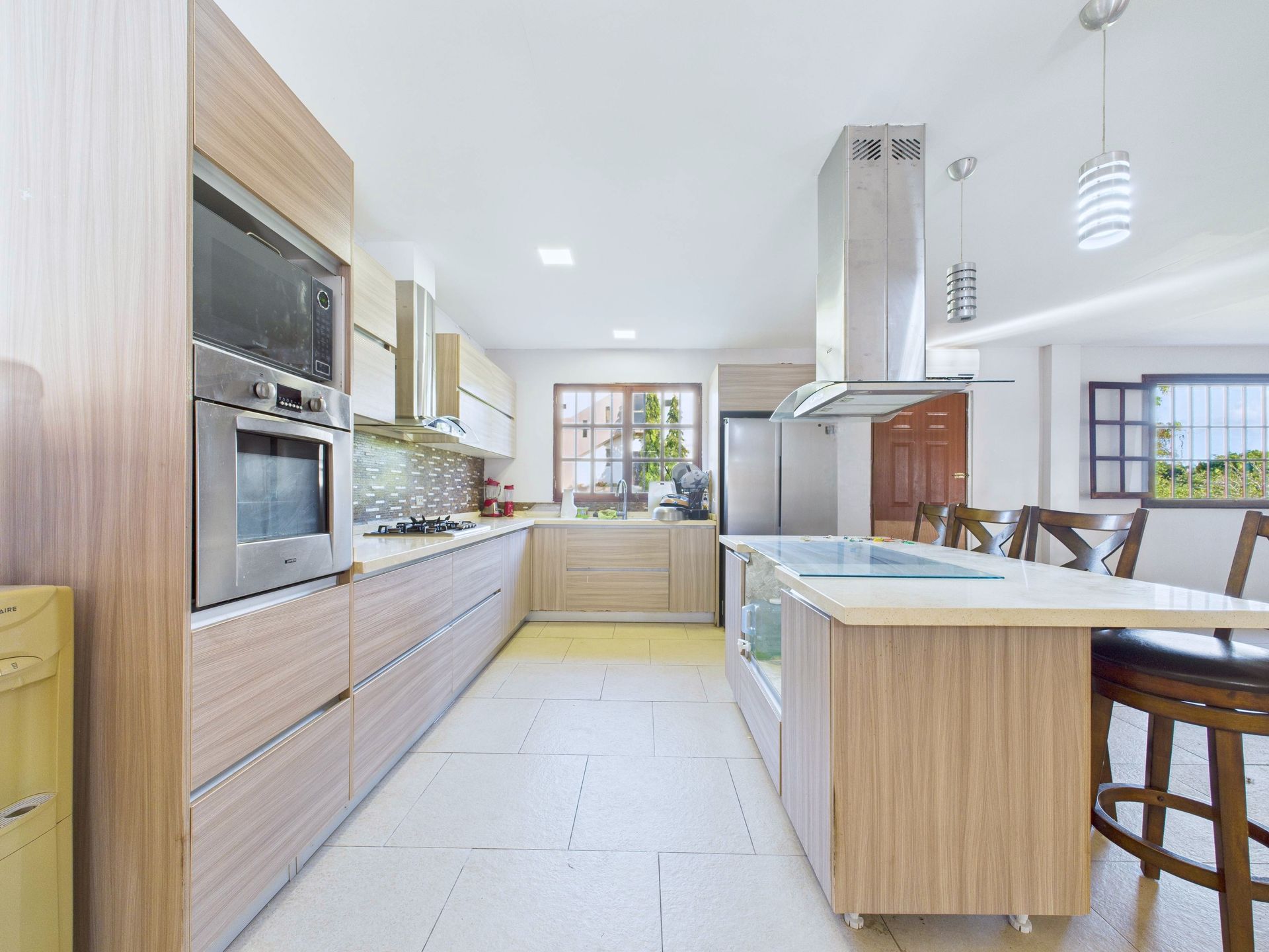 Cocina moderna con gabinetes de madera, electrodomésticos de acero inoxidable e isla con estufa.