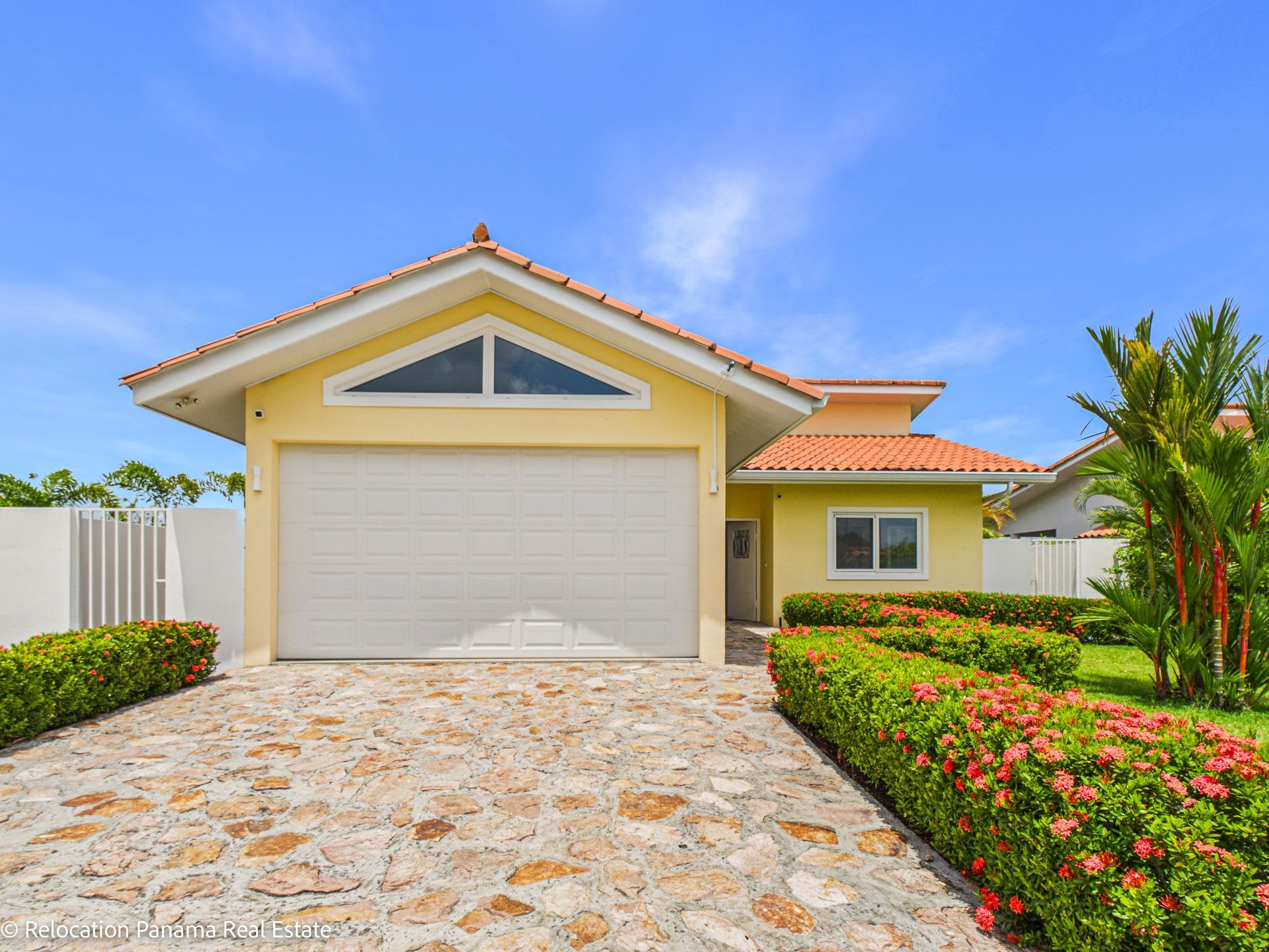 Cocina con isla de asientos, gabinetes de madera clara, electrodomésticos de acero inoxidable e iluminación colgante.