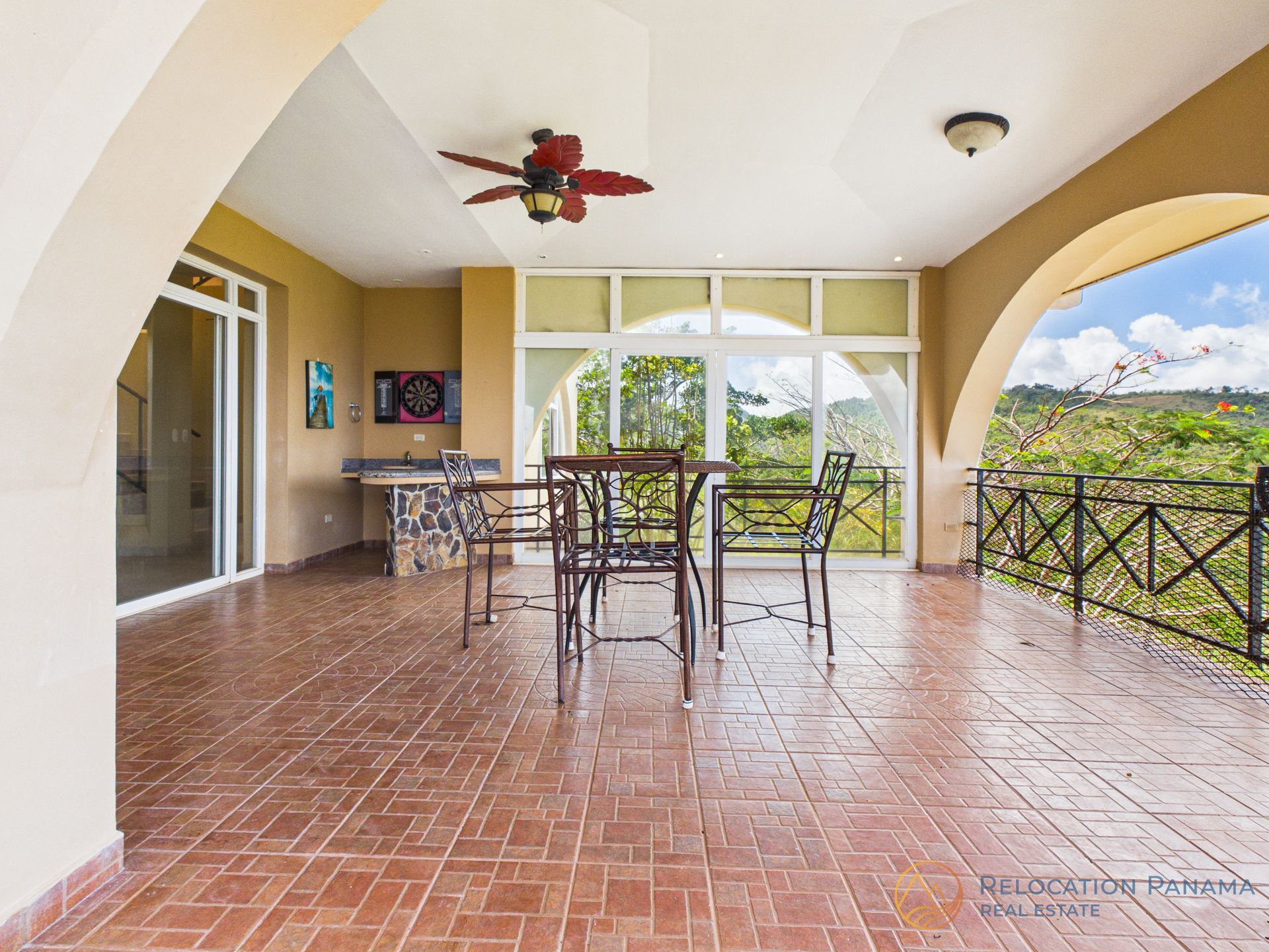 Amplio patio cubierto con suelos de baldosas de terracota, un conjunto de comedor, una zona de cocina al aire libre y vistas panorámicas del paisaje.