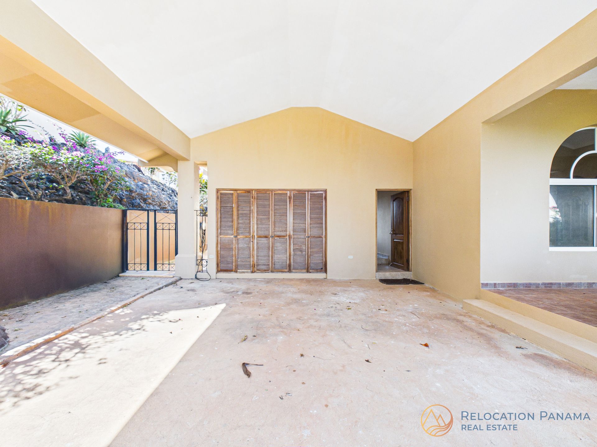 Un amplio garaje cubierto con paredes de color beige, puerta de garaje de madera con listones y puerta de entrada contigua.