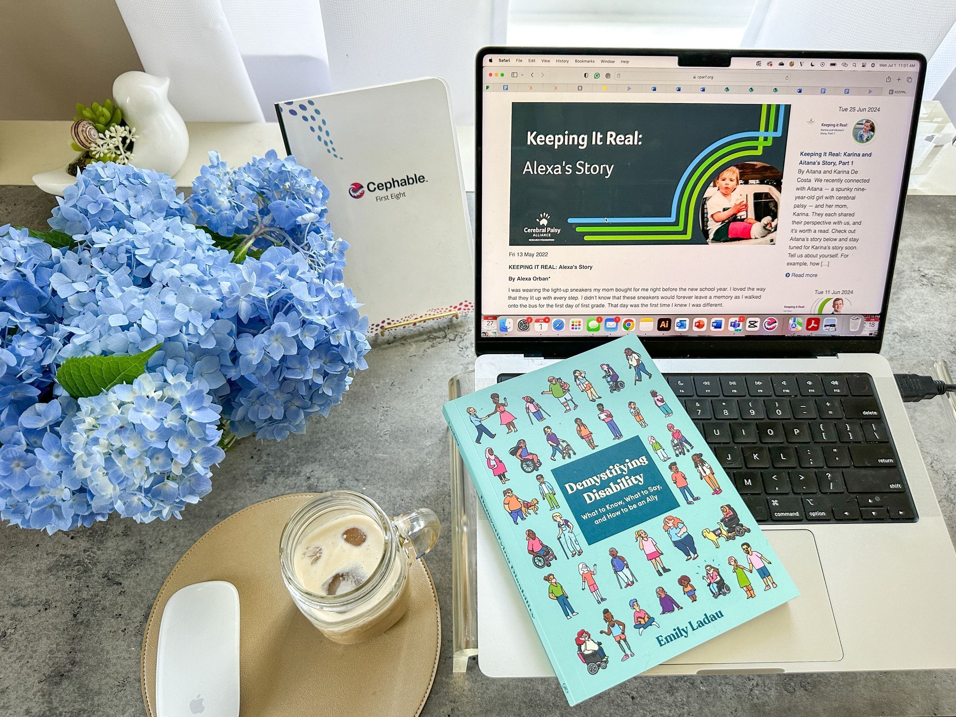 A photo of Alexa's desk. On the left, a bouquet of blue hydrangeas sits next to a cup of iced coffee