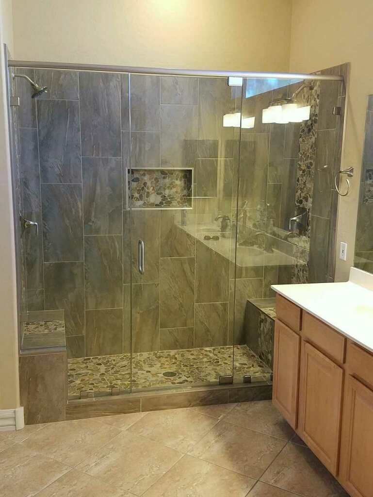 Glass-enclosed walk-in shower with beige tile and a vanity sink on the right