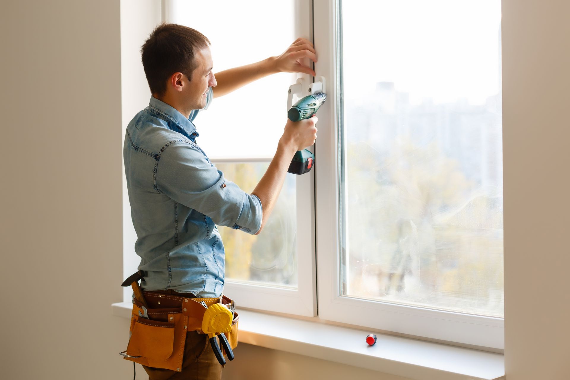Person using a drill to install window blinds in a bright room