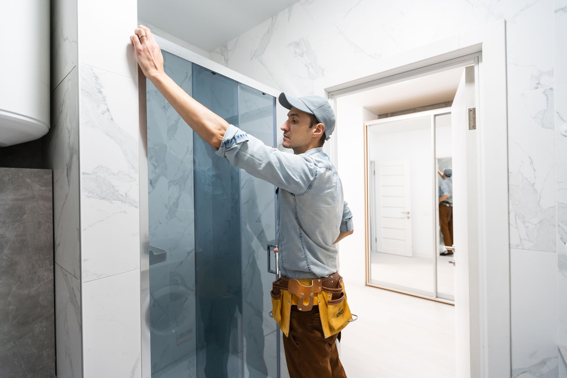 Worker installing wallpaper in a bright hallway, measuring a wall with a tape measure