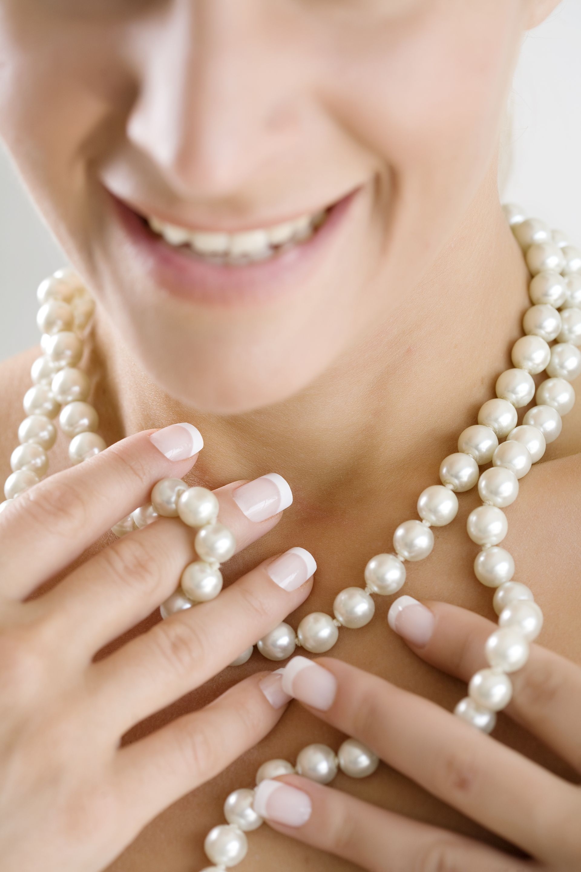 Una donna indossa una collana di perle e sorride