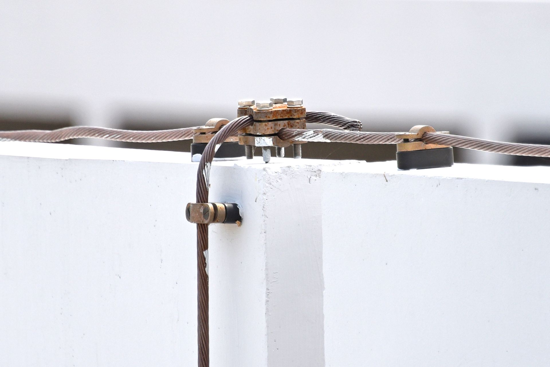 Grounding wires connected to a metal connector on a white wall.