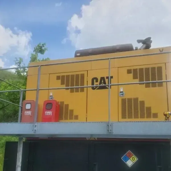 Yellow CAT generator on a platform with safety equipment and a hazardous materials sign.