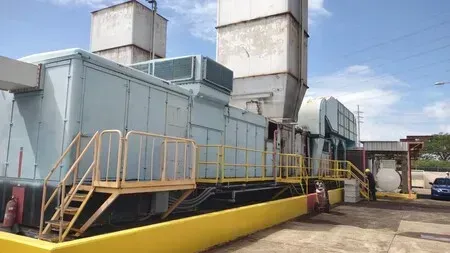 Industrial machinery with stairs, yellow and gray paint, and blue sky.