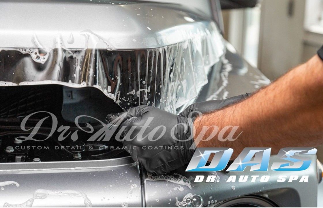 man installing paint protection film on the hood of a car