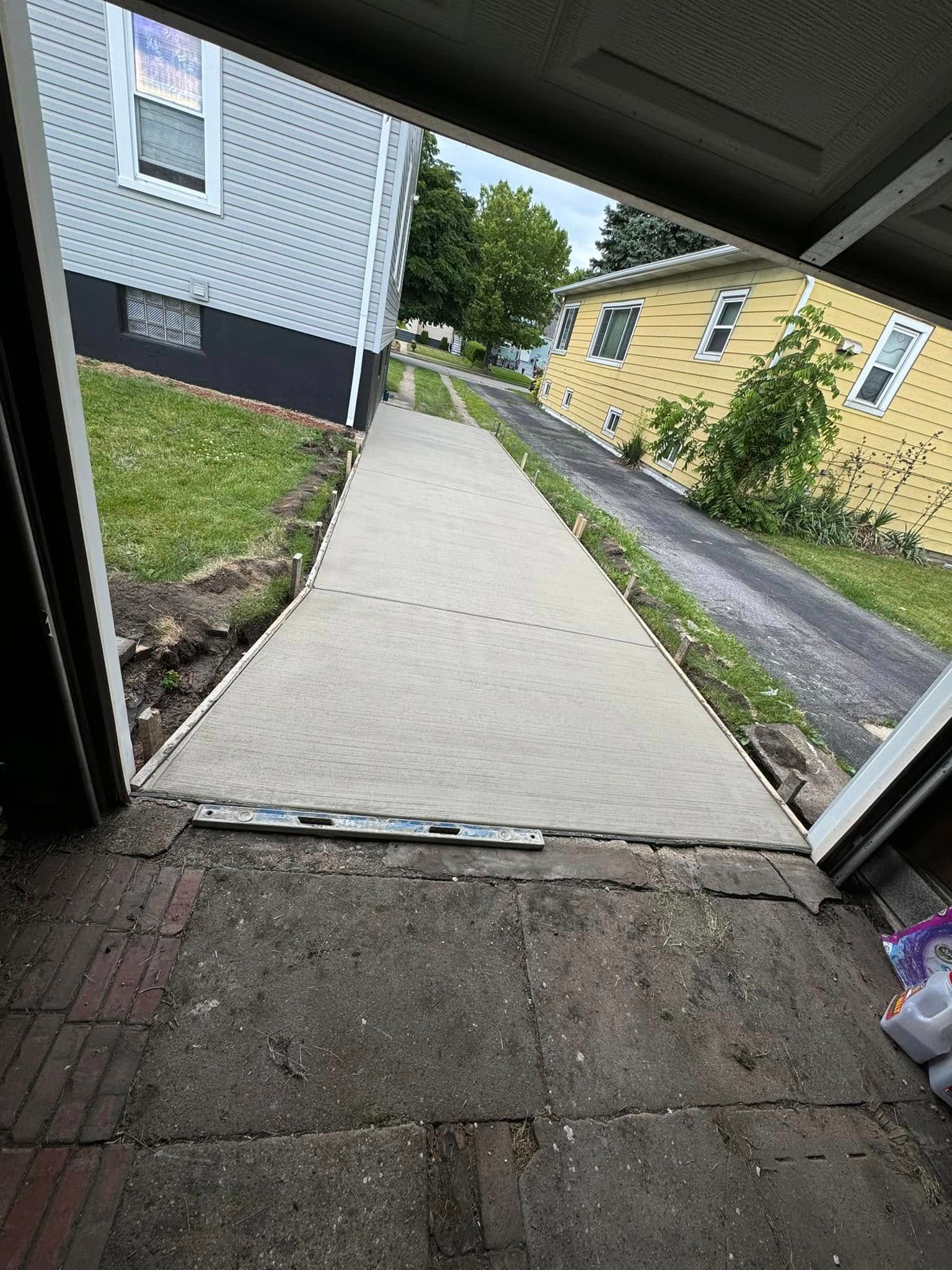 A concrete walkway is being built in front of a house.
