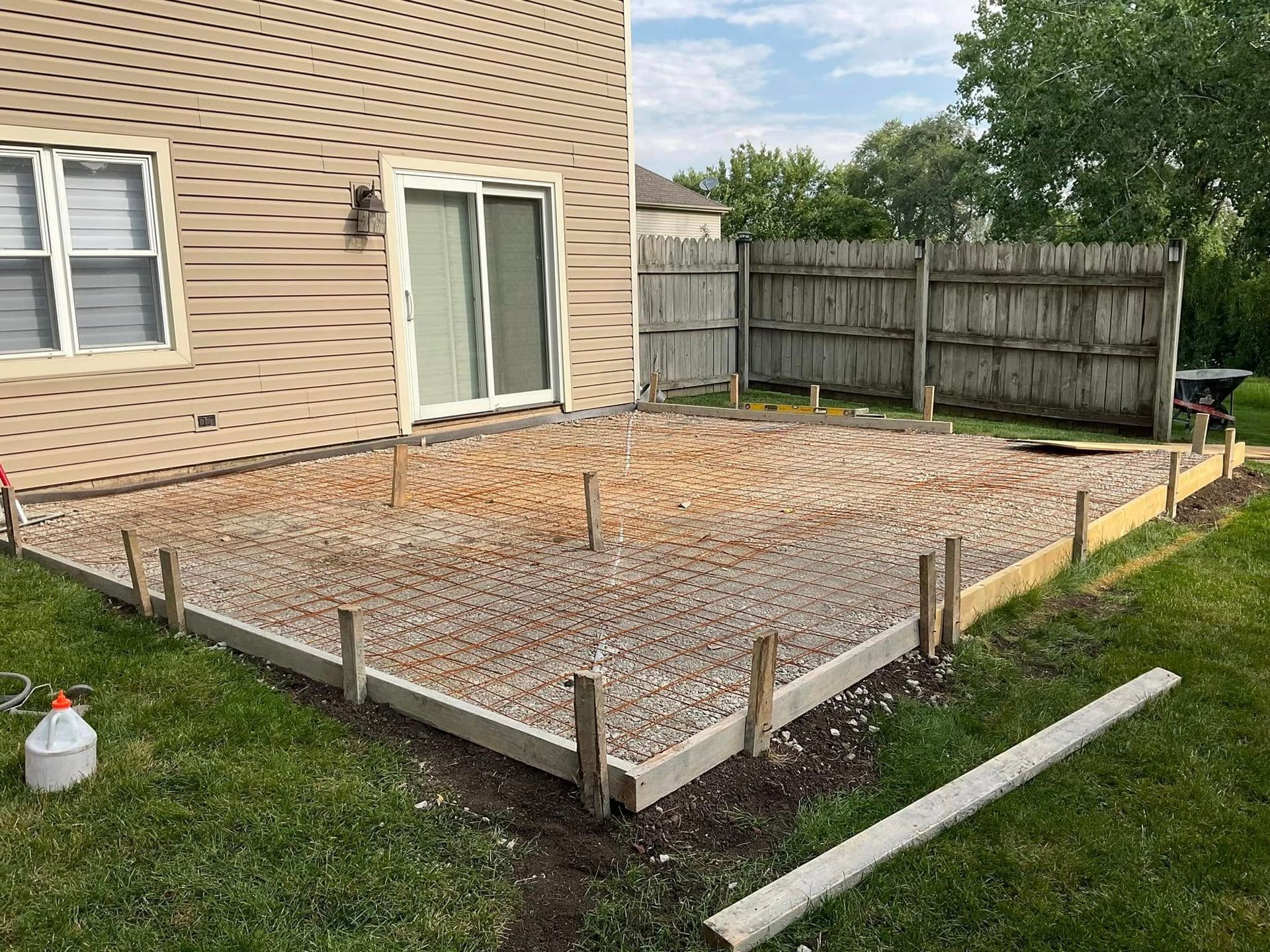 A concrete patio is being built in the backyard of a house.