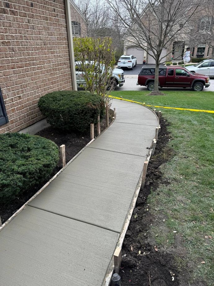 A concrete walkway is being built in front of a brick building.