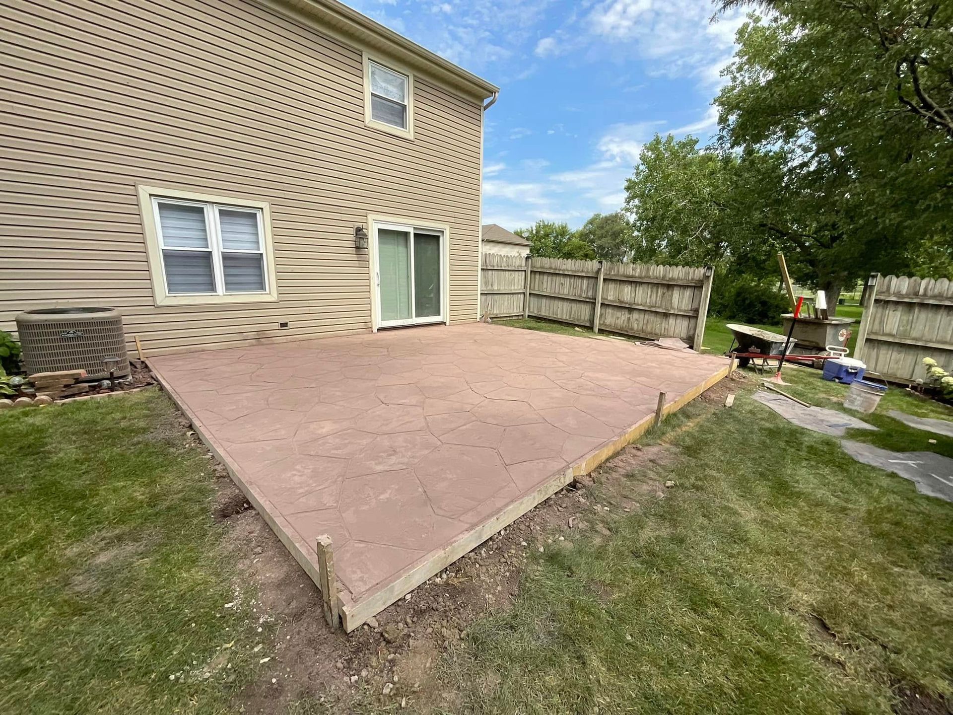 A patio is being built in the backyard of a house.