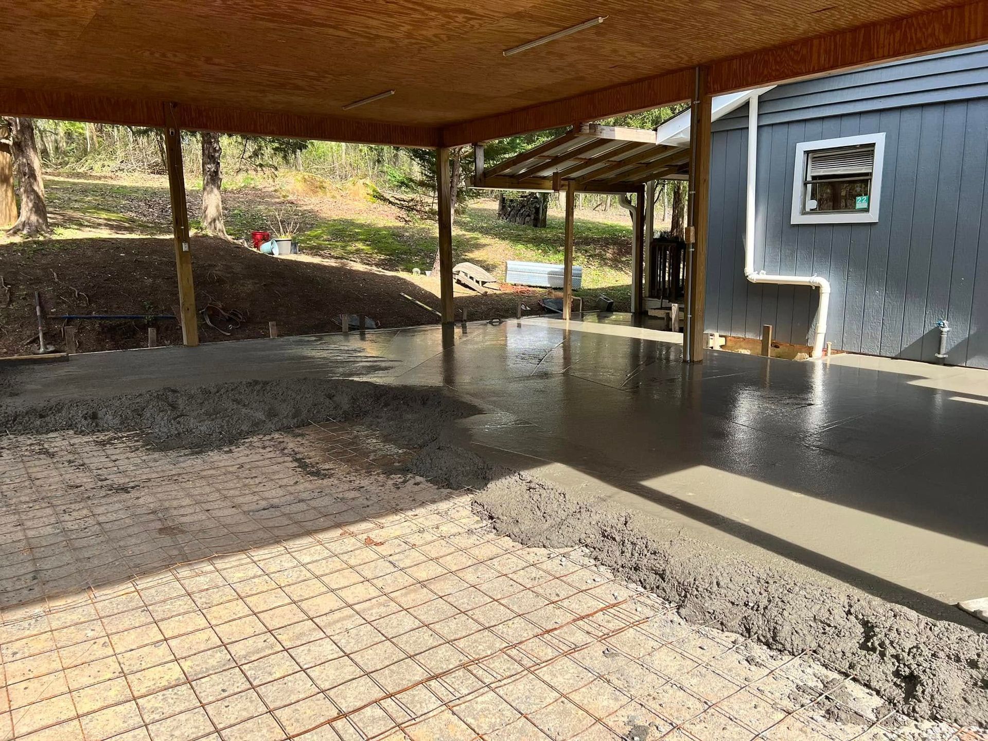 A concrete floor is being poured in a garage under a canopy.