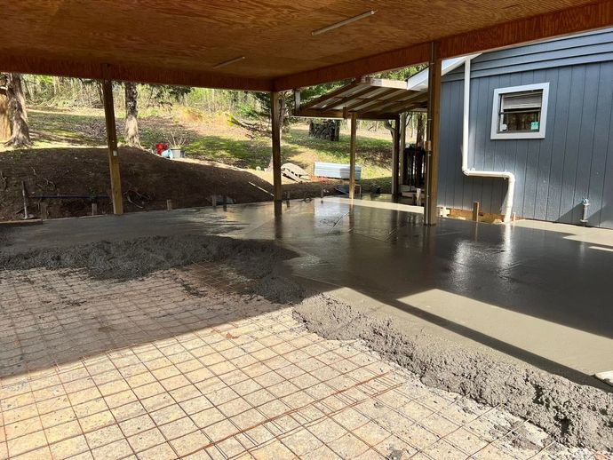 A concrete floor is being poured in a garage under a canopy.