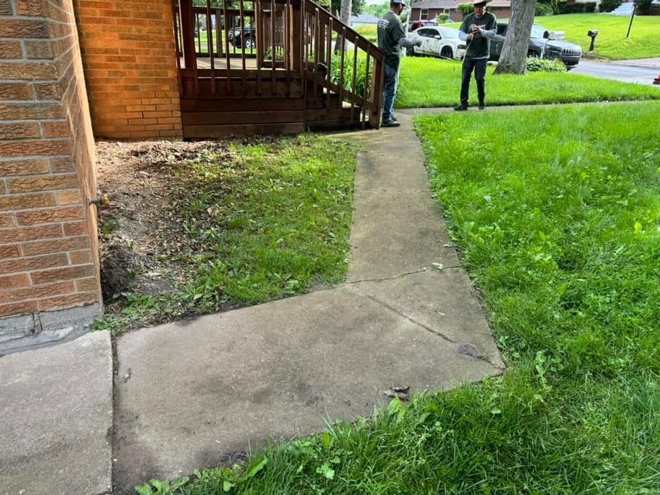 A couple of people standing on a sidewalk in front of a house.