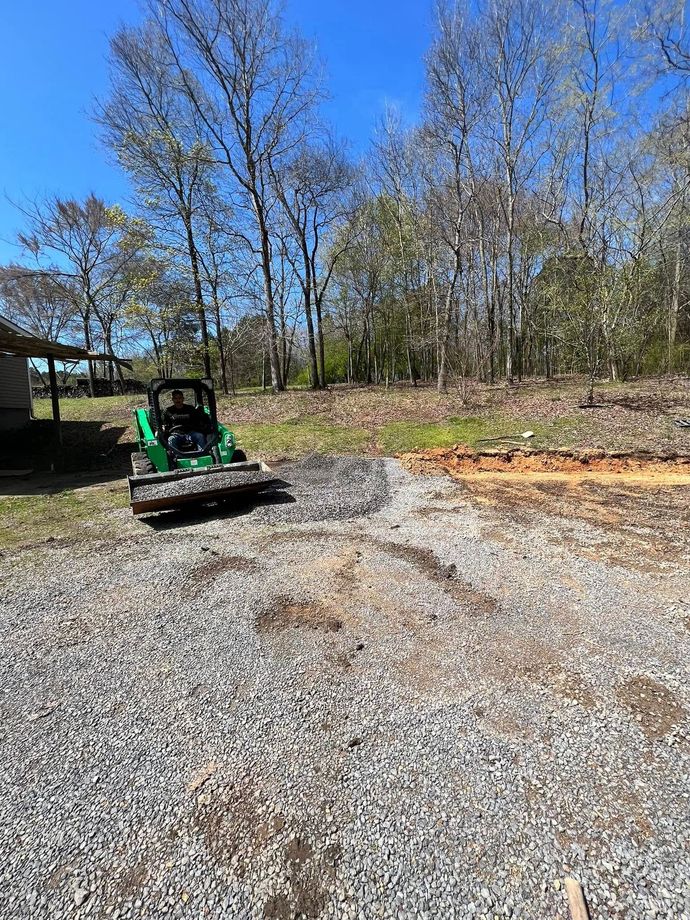A green tractor is parked in a gravel lot.