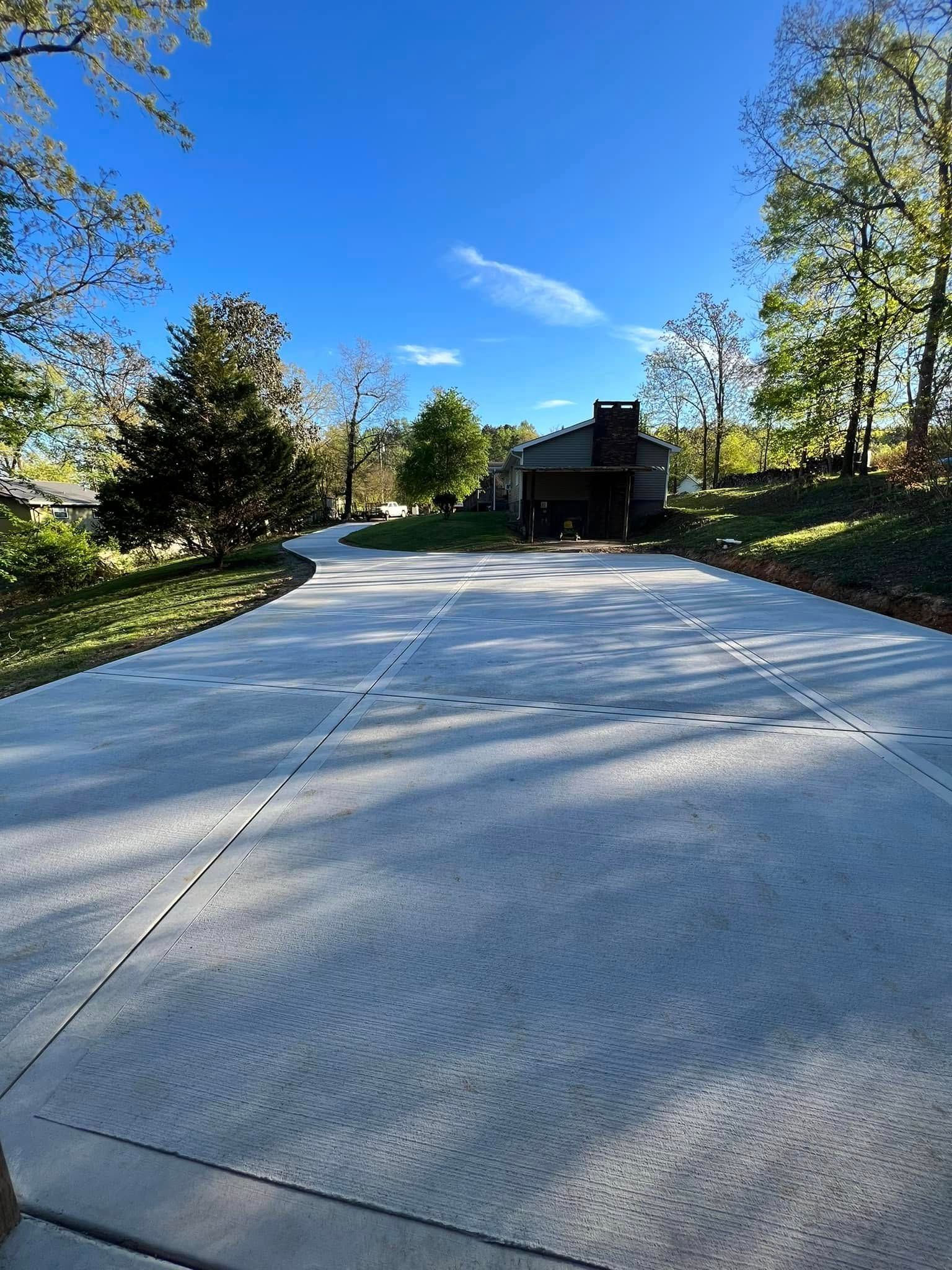 A concrete driveway leading to a house on a sunny day.