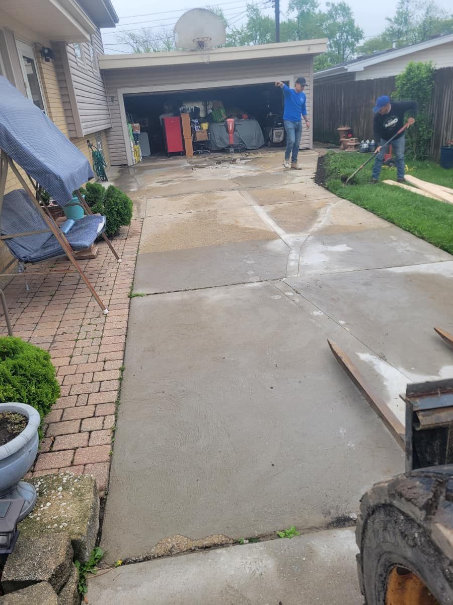 A group of people are working on a driveway in front of a house.