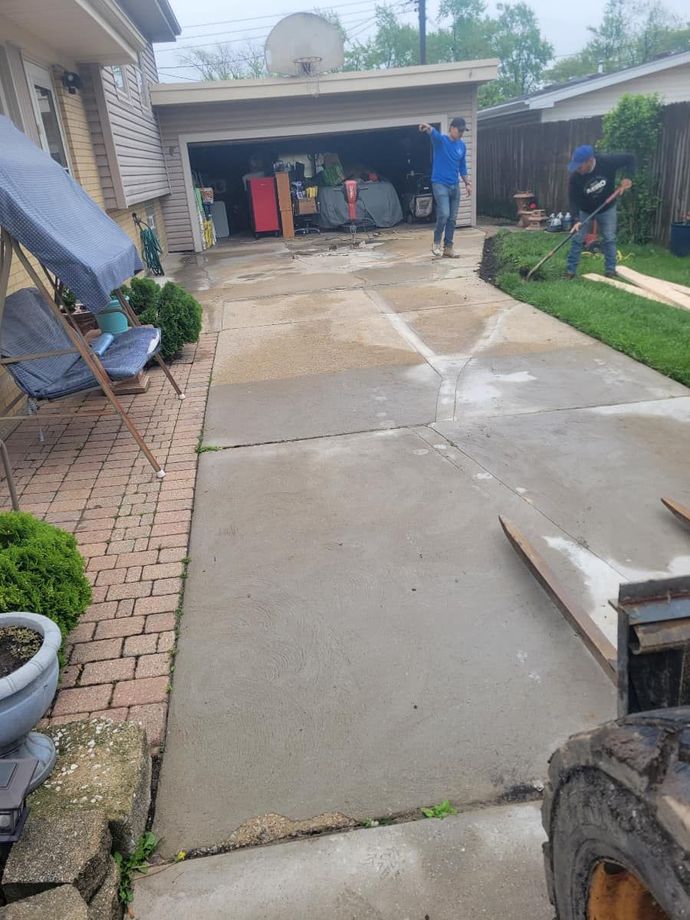 A group of people are working on a driveway in front of a house.
