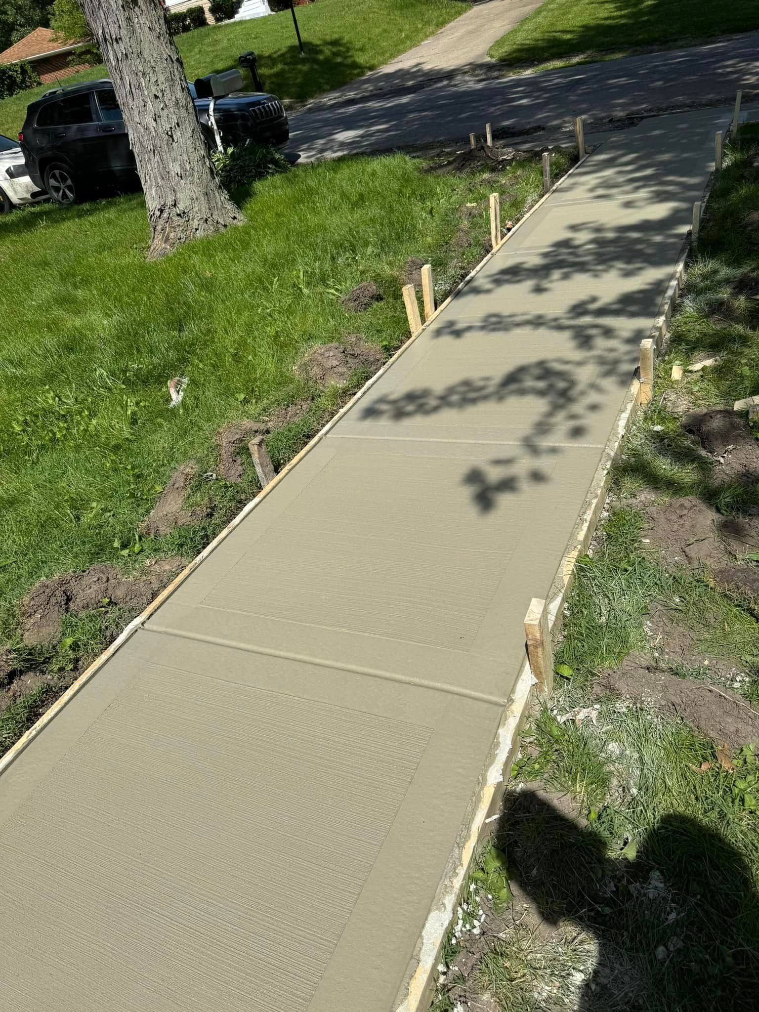 A concrete walkway is being built in the grass.