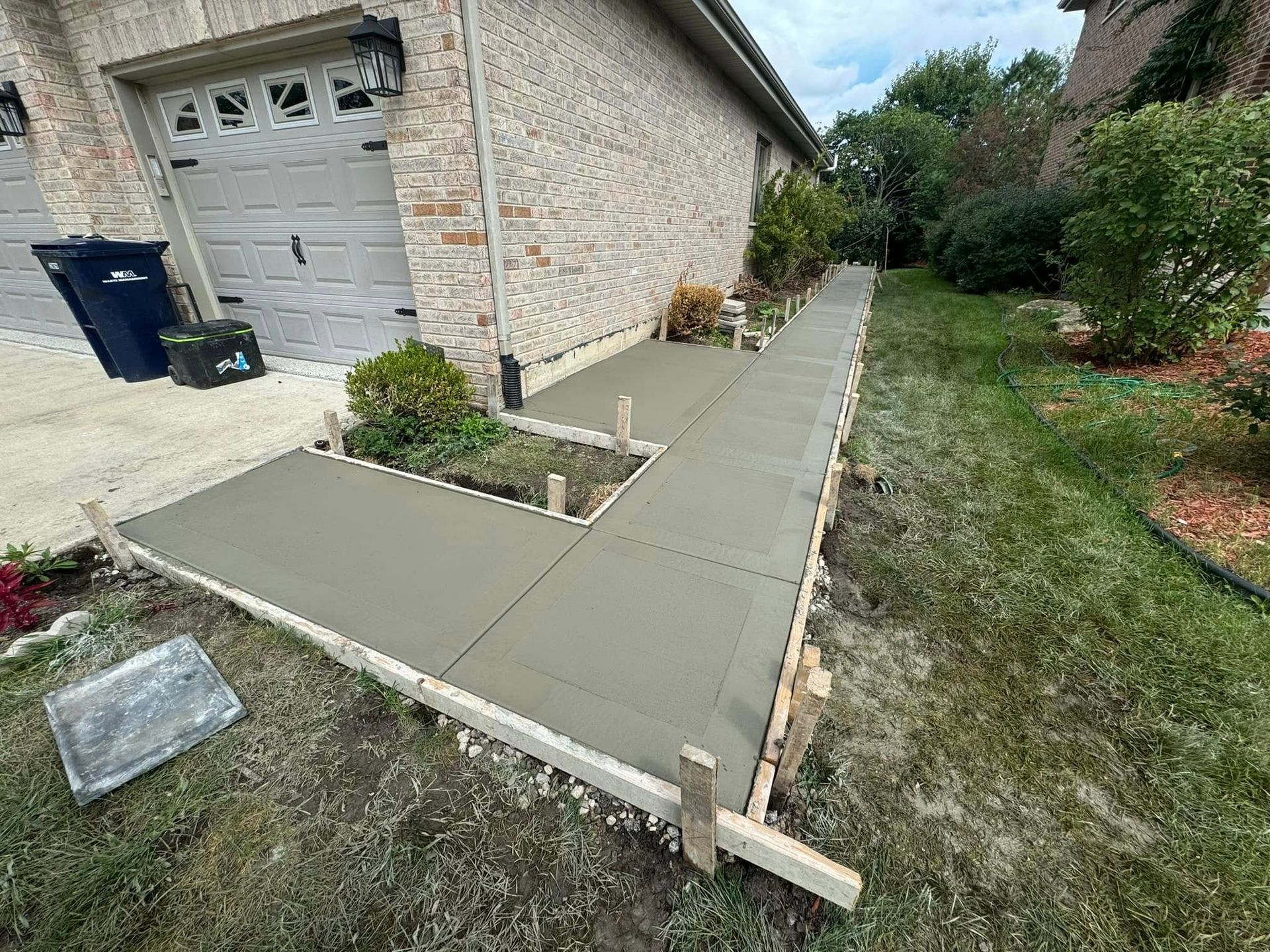 A concrete walkway is being built in front of a house.