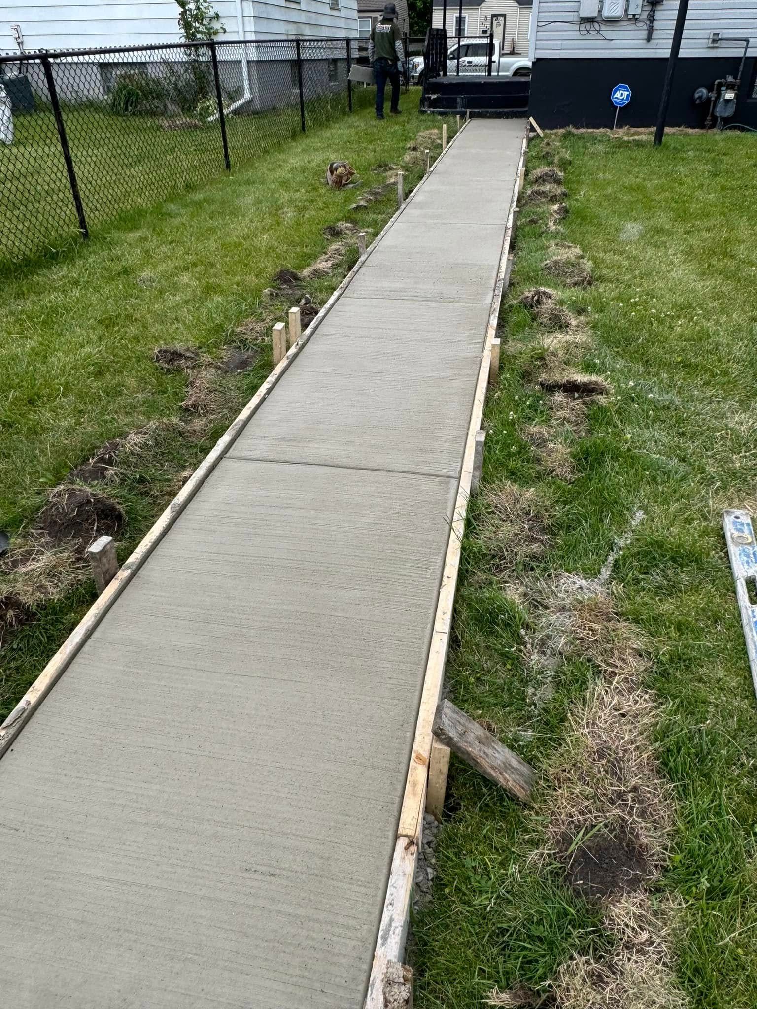 A concrete walkway is being built in a backyard.