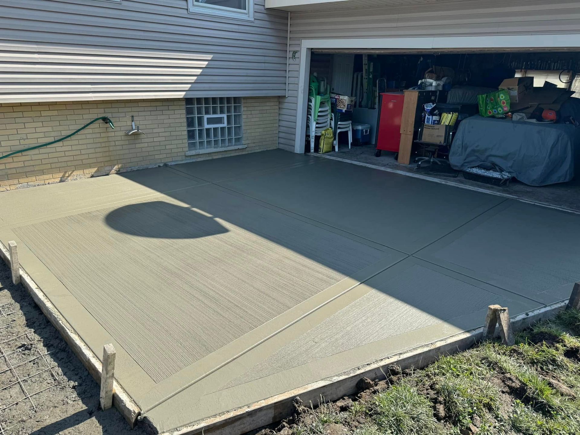 A concrete driveway is being built in front of a garage.