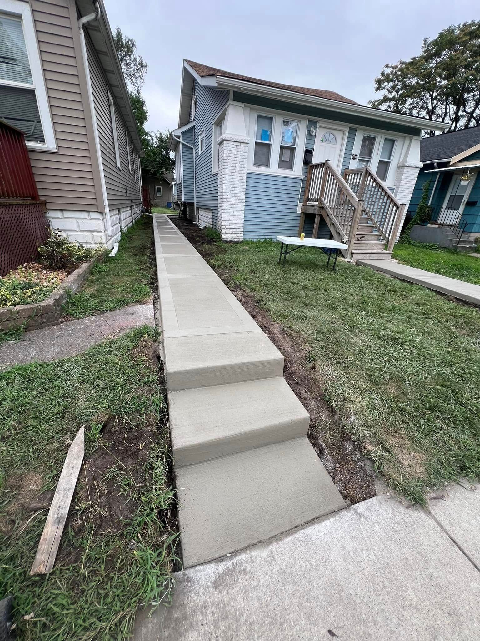 A concrete walkway is being built in front of a house.
