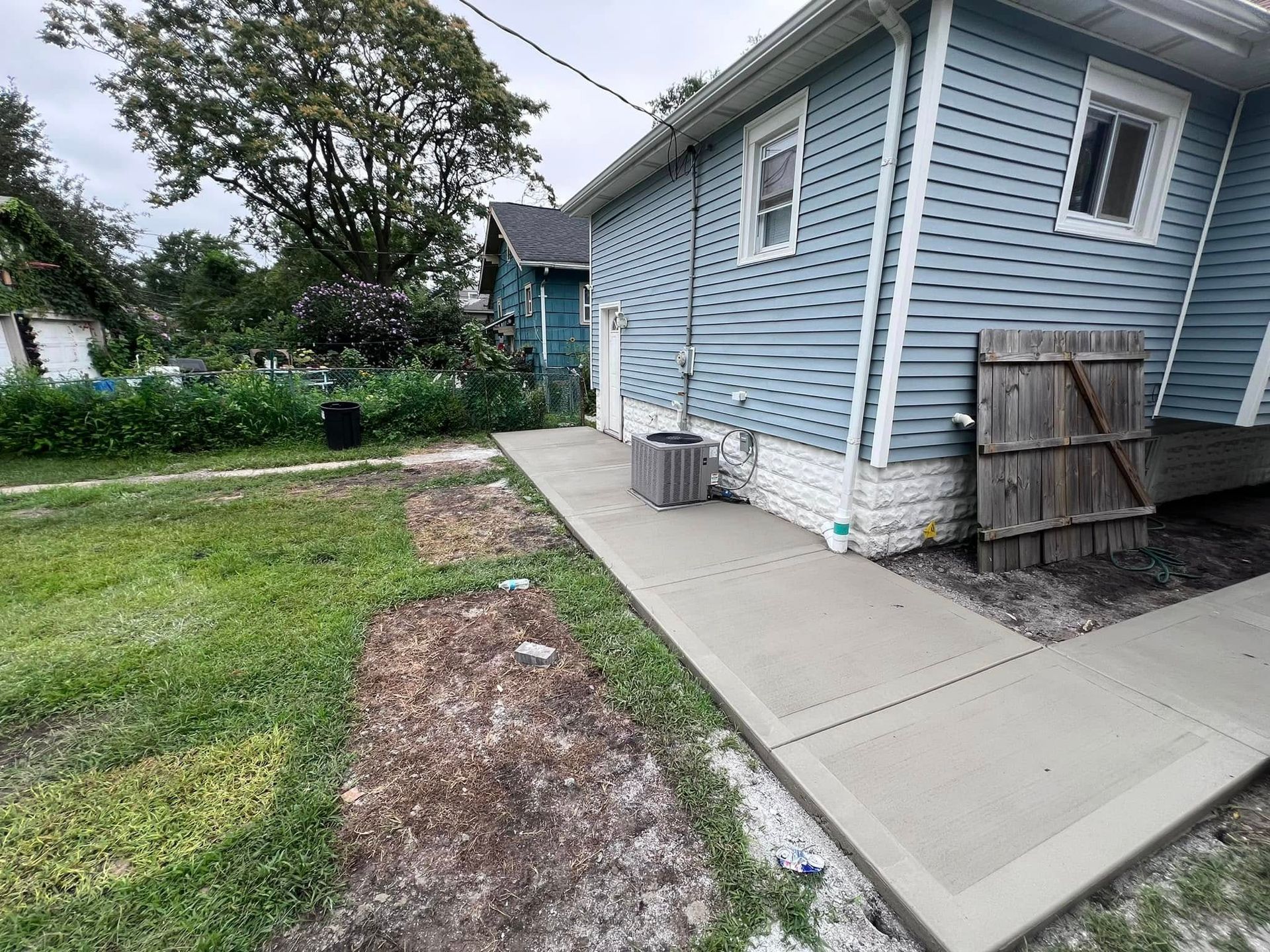 A blue house with a concrete walkway leading to it.