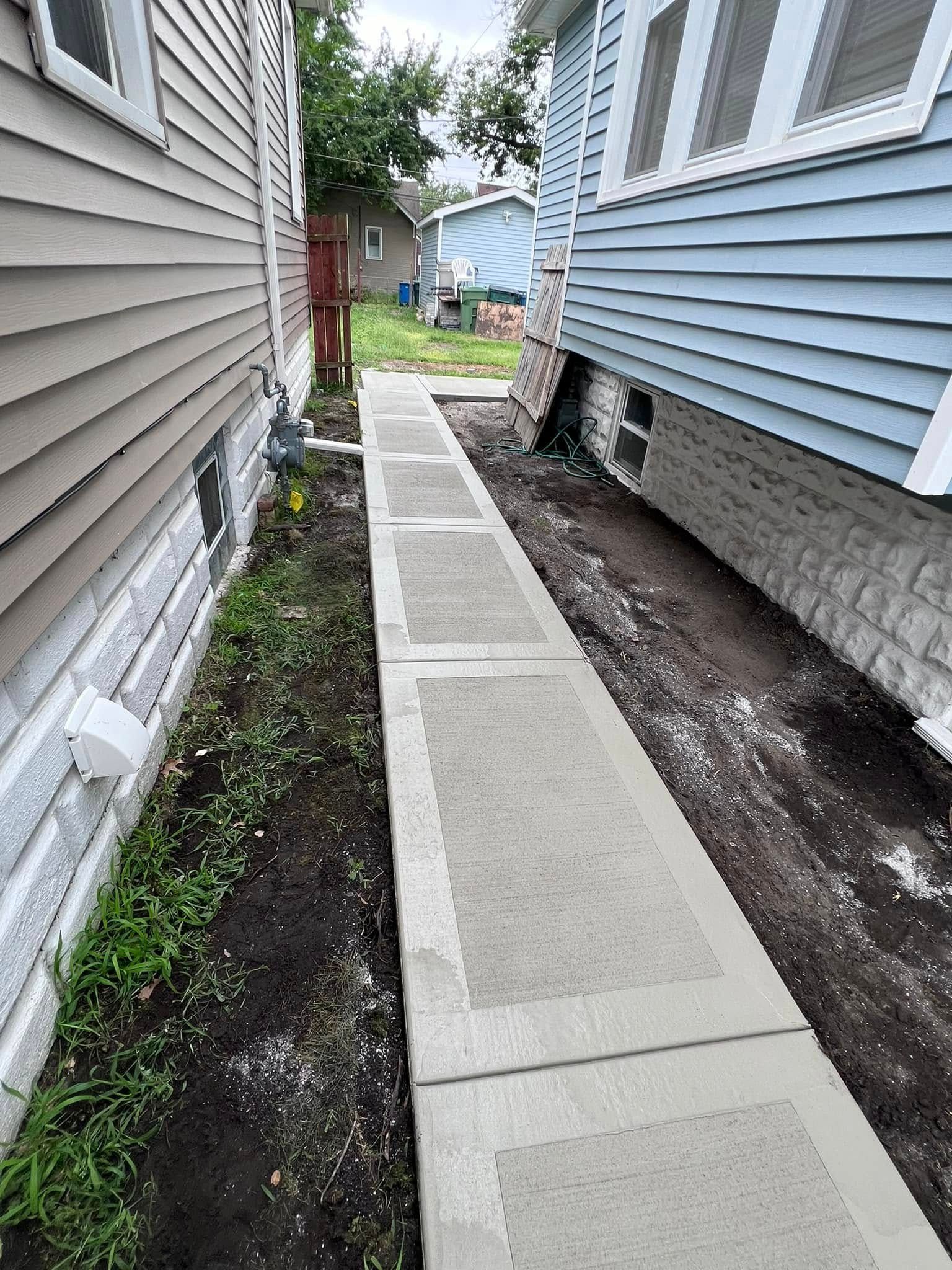 A sidewalk is being built between two houses.