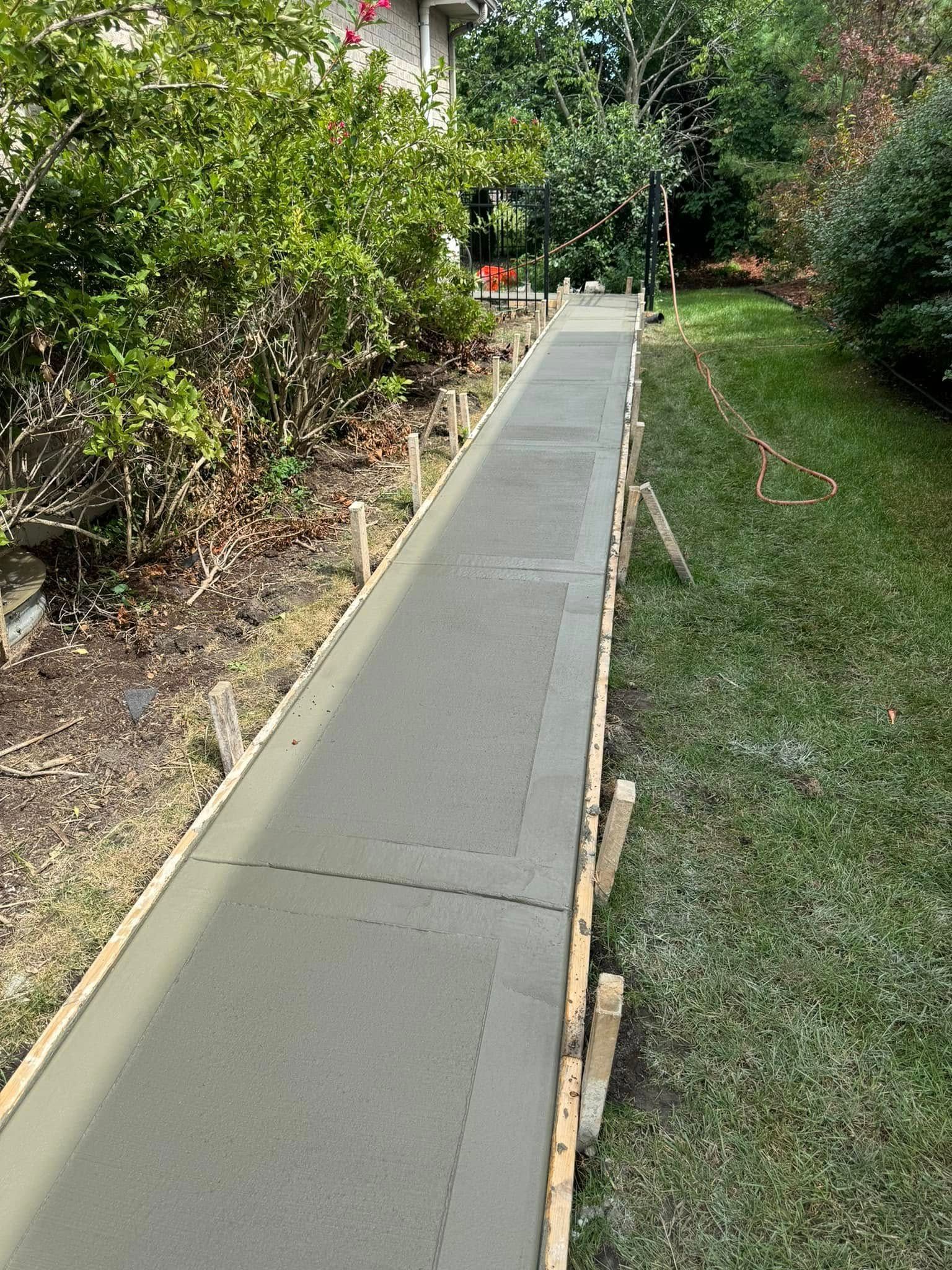 A concrete walkway is being built in a backyard.