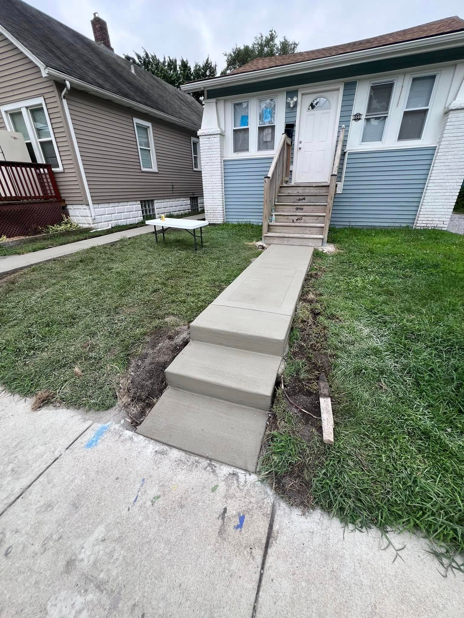 There is a concrete walkway leading to the front of a house.