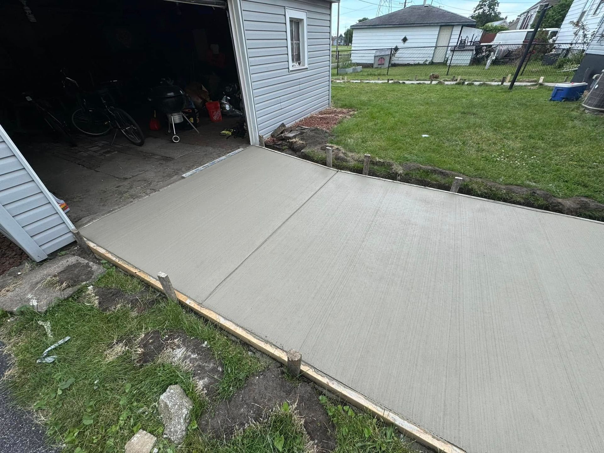A concrete driveway is being built in front of a garage.