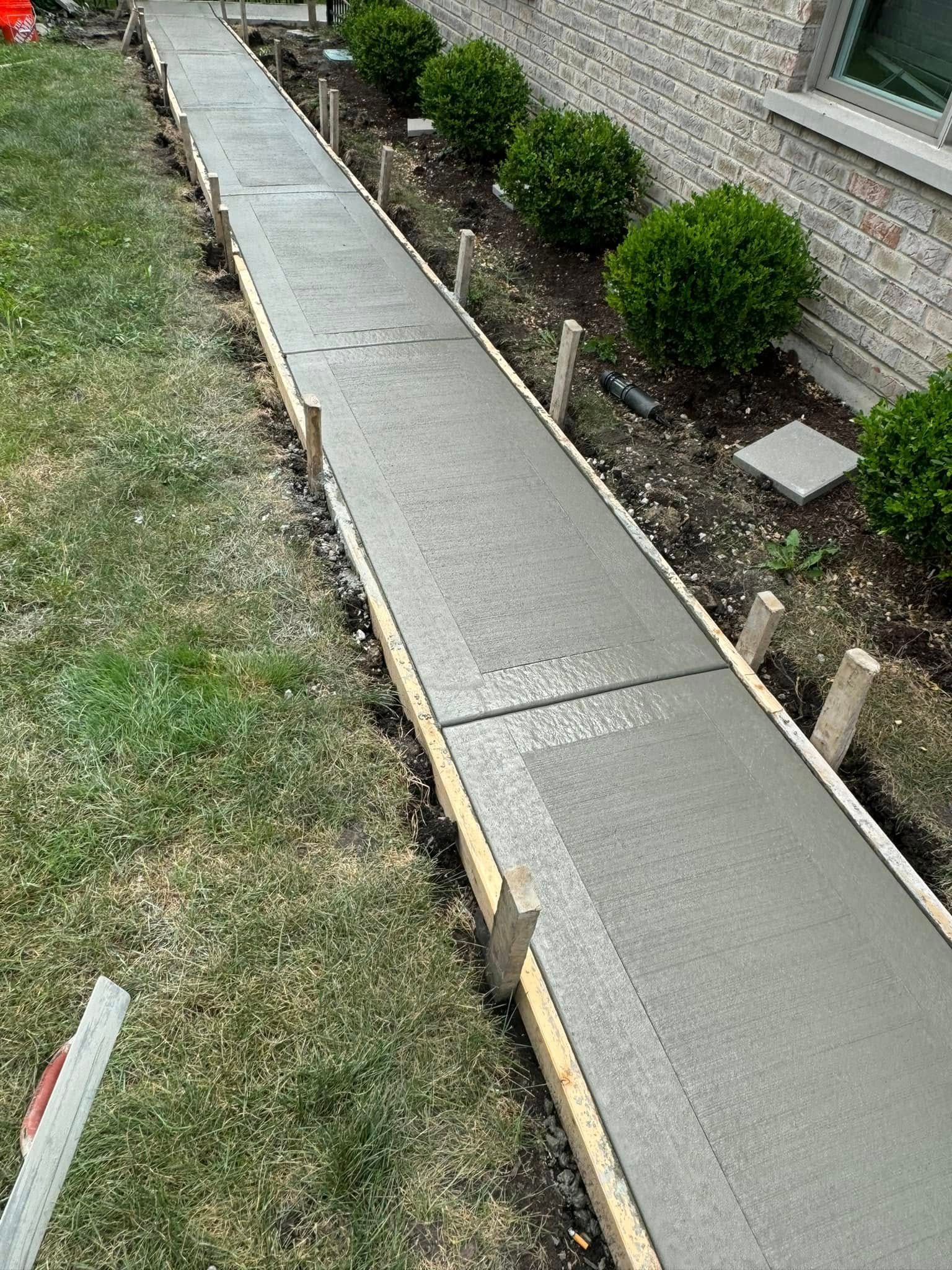 A concrete walkway is being built in front of a house.