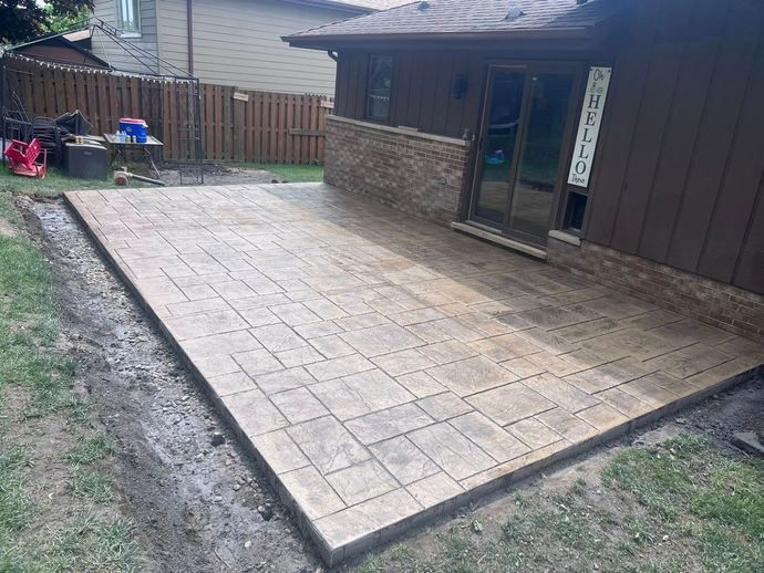 A patio is being built in the backyard of a house.